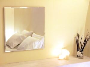 a mirror on a wall above a bed with white pillows at Alafouzou Cave Loft by SV in Oia