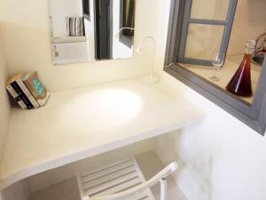 y baño con lavabo blanco y espejo. en Alafouzou Cave Loft by SV, en Oia