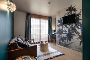 sala de estar con sofá y TV en la pared en Best Western Aquakub, en Aix-les-Bains