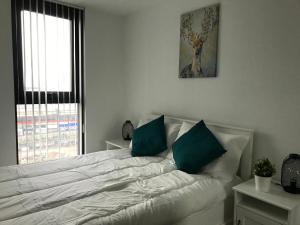 a white bed with green pillows in a bedroom at Lapwing - Sleeps up to 6, Fabulous panoramic city views, 12th Floor 2 bed city centre apartment, Perfect for work or leisure! in Sheffield