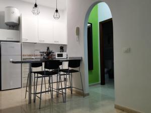 a kitchen with a counter with stools and a green wall at 23 DE ENERO in La Restinga