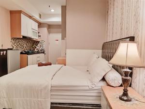 um quarto com uma cama e uma mesa com um candeeiro em Grand Kamala Lagoon by 21 Room Netflix em Bekasi