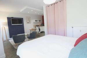 a bedroom with a white bed and a kitchen at City Bagot in Saint-Brieuc