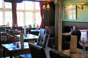 a restaurant with wooden tables and chairs and windows at The White Horse in Beyton