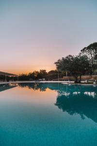 ein großer Pool mit blauem Wasser und Sonnenuntergang im Hintergrund in der Unterkunft Leano Agriresort in Piazza Armerina