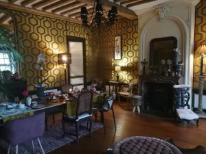 uma sala de estar com uma mesa e cadeiras e uma lareira em Hôtel particulier "le clos de la croix" em Bayeux