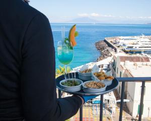 a person holding a tray of food and a drink at Relais Maresca Luxury Small Hotel & Terrace Restaurant in Capri