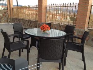 una mesa y sillas con un jarrón de flores en el patio en Alojamientos El Chorro, en Los Navalucillos