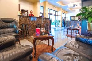 a bar with leather furniture and a man standing behind a counter at Viand Hotel - Premium All Inclusive in Sunny Beach