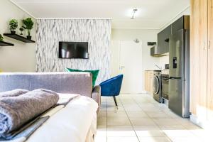 a living room with a couch and a kitchen at Insaka's 2 Greenlee Apartment - Greenlee Lifestyle Centre, Sandton in Sandown