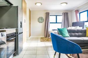 a living room with a couch and a blue chair at Insaka's 2 Greenlee Apartment - Greenlee Lifestyle Centre, Sandton in Sandown