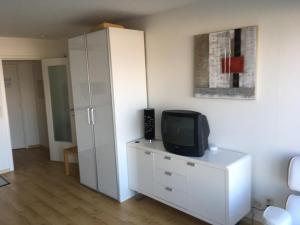 a room with a tv on a dresser with a white cabinet at prachtige studio met havenzicht in Ostend