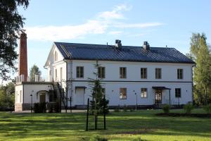 ein großes weißes Haus mit einem Kamin auf einem Rasen in der Unterkunft Hotelli Kartanon Meijeri in Mäntsälä + 33 Fotos