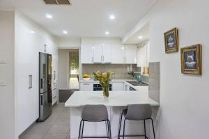 a white kitchen with a table and two chairs at Plantation Haven in Mildura