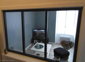 Pokój z dużym szklanym oknem i telewizorem w obiekcie Le 46 Clos Vert w mieście Erquy