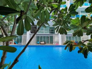 a blue swimming pool with palm trees in front of a building at My Resort Huahin by Vas in Hua Hin