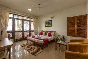 a bedroom with a bed and a table and a couch at KSTDC Hotel Mayura Pine Top Nandi Hills in Nandi