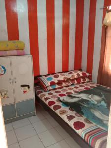 una piccola camera con letto e parete a righe di Pondok orange ciwidey a Bandung