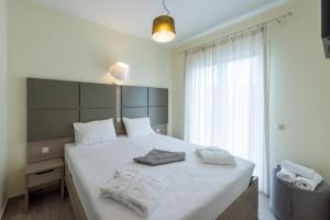 a bedroom with a bed with white sheets and a window at Venus Villa with Private Pool, 2min to the Beach in Finikounta +18 photos