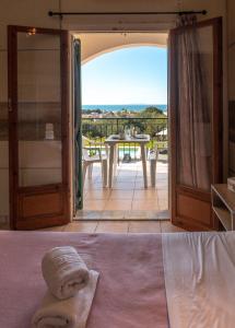 een slaapkamer met een deur naar een balkon met een tafel bij Catamaran Corfu Aparthotel in Acharavi