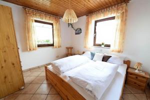 a bedroom with a large white bed with two windows at Gästehaus Monalisa in Grabenstätt