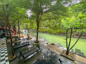 eine Gruppe Bänke in einem Park neben einem Fluss in der Unterkunft Natthapon Resort Kaeng Kachan in Kaeng Kachan