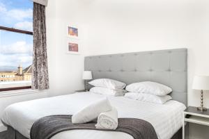 a bedroom with a large white bed with a window at Kelpies Serviced Apartments in Falkirk