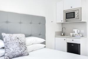 a bedroom with a bed with a microwave and a kitchen at Kelpies Serviced Apartments in Falkirk