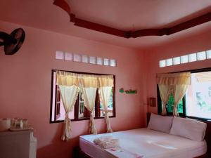 a bedroom with a bed and two windows at Silver Beach Bungalow in Haad Yao