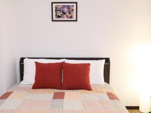 a bedroom with a bed with two red pillows at ケイアイコンホテルズ 池下 in Chikusachō