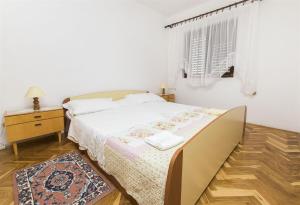 a white bedroom with a bed and a night stand at Apartment Danica in Nin