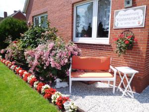 eine Bank vor einem Gebäude mit Blumen in der Unterkunft Ferienwohnung Küstensnack in Cuxhaven