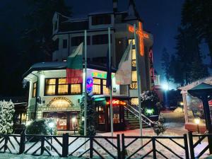 un edificio con banderas delante de él por la noche en Alpin Borovets, Алпин Боровец en Borovets