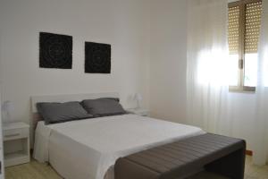 um quarto branco com uma cama e um banco em Cala Rosa em Torre Lapillo