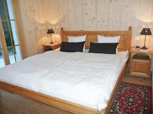 a bedroom with a large bed with two tables and two lamps at Chalet Chalet La Poya by Interhome in Moleson +24 photos