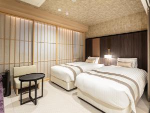 a hotel room with two beds and a table at Hotel Musse Kyoto Shijo Kawaramachi Meitetsu in Kyoto