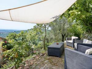 a patio with chairs and an umbrella and trees at Apartment I Limoni - BUT151 by Interhome in Buti