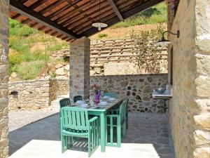 San Martino in FreddanaにあるHoliday Home Olivo by Interhomeの木製の屋根の下に緑のテーブルと椅子が備わるパティオ