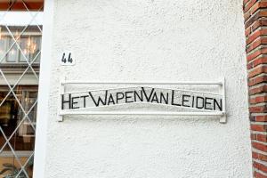 um sinal na lateral de um edifício branco em Het Wapen van Leiden em Appingedam