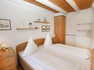 Schlafzimmer mit einem weißen Bett mit einem Kopfteil aus Holz in der Unterkunft Holiday Home Klaffmuschel by Interhome in Norddeich