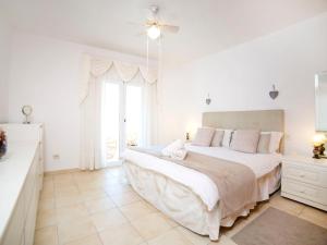 a white bedroom with a large bed and a window at Villa Bougainvillea by Interhome in La Canuta