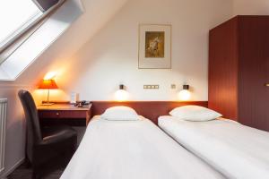 two beds in a room with a desk and a window at Het Wapen van Leiden in Appingedam