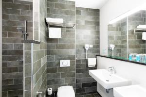 ein Badezimmer mit einem Waschbecken, einem WC und einem Spiegel in der Unterkunft Bastion Hotel Leeuwarden in Leeuwarden