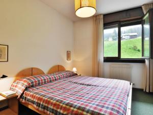 ein Schlafzimmer mit einem Bett mit einer karierten Decke in der Unterkunft Apartment Enrosadira-5 by Interhome in Alba di Canazei