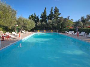 a large blue swimming pool with chairs and a table at Apartment Borgoverde-1 by Interhome in Imperia