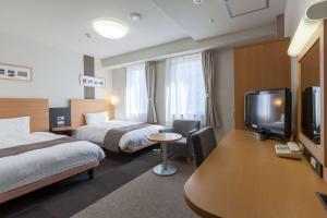 a hotel room with two beds and a flat screen tv at Comfort Hotel Hiroshima Otemachi in Hiroshima