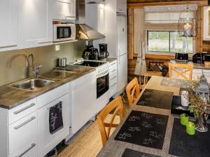 a kitchen with white cabinets and a table with a tableablish at Holiday Home Peurankuoppa by Interhome in Lemmenjoki