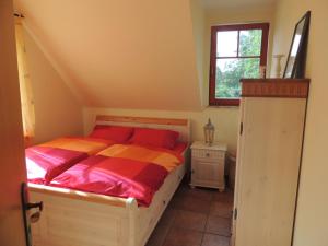 a bedroom with a bed with red pillows and a window at Boddenblick in Groß Kordshagen