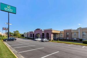 Quality Inn & Suites - Greensboro-High Point في جرينسبورو: وجود علامة على الشارع في موقف السيارات أمام المبنى