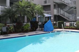 a large swimming pool in a hotel with a blue umbrella in the middle at Quality Inn Miami Airport - Doral in Miami